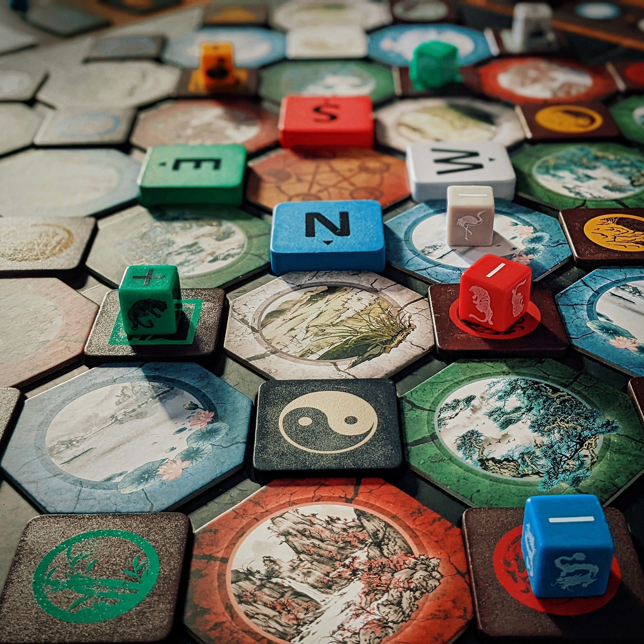 Close-up of animal pieces, chi markers and direction tiles on Wu Wei's illustrated board